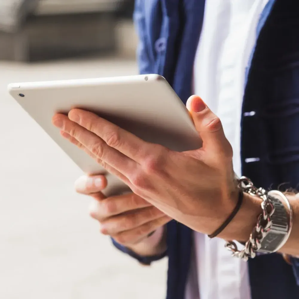 Hände halten ein Tablet im Außendienst